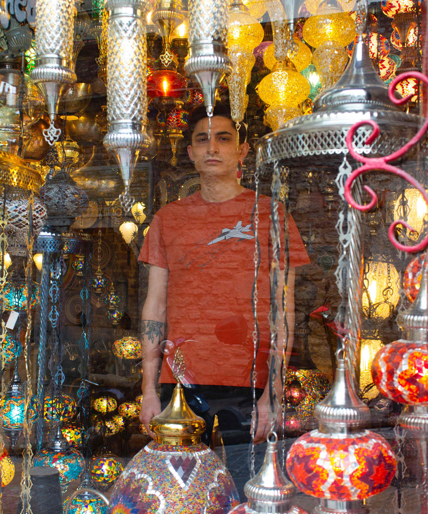 A guy is wearing Aponia Plane T-shirt and standing behind a show case of Turkish lamps 